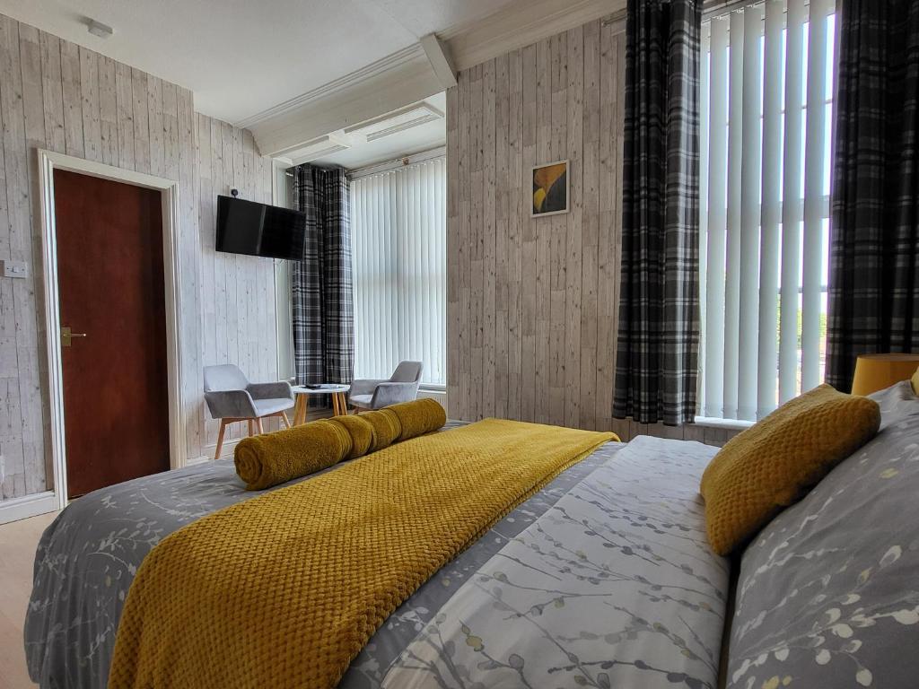 a bedroom with a bed with a yellow blanket on it at Daffodil Guest House in Filey