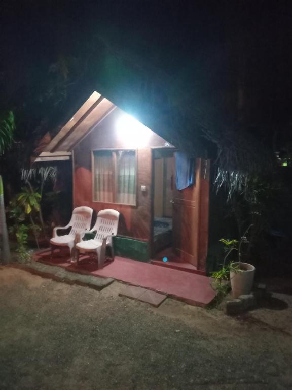 une maison avec 2 chaises et une terrasse couverte la nuit dans l'établissement Blue Ocean Cabana, à Trincomalee
