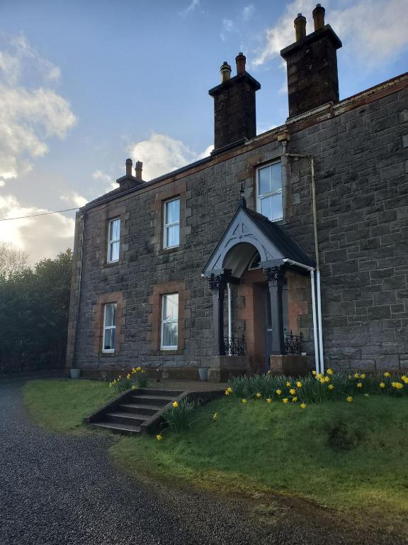 an old brick house with flowers in front of it at McCaig's View in Oban