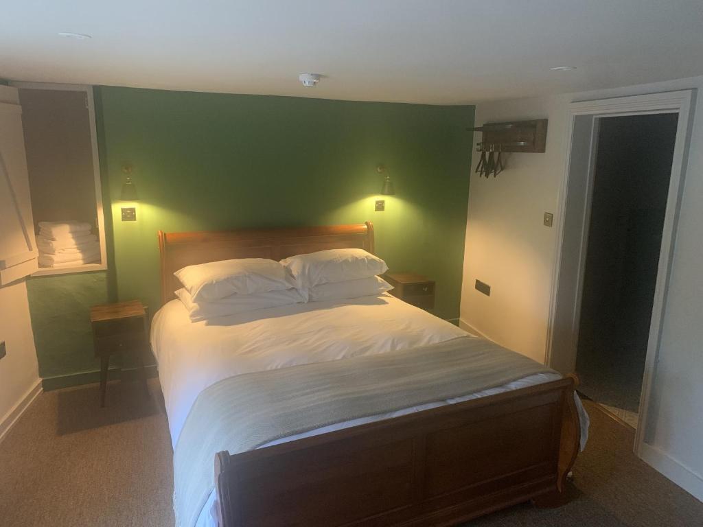 a bedroom with a bed with a green wall at The Fox & Hounds Inn in Dorchester