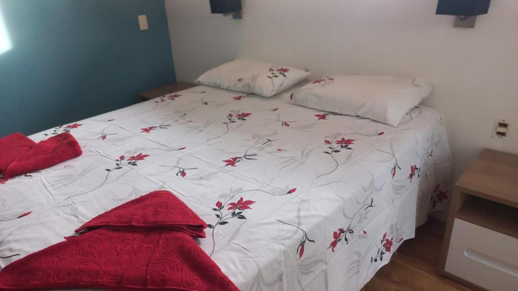 ein Bett mit einer weißen Bettdecke und roten Blumen drauf in der Unterkunft Casa 11 in Campinas