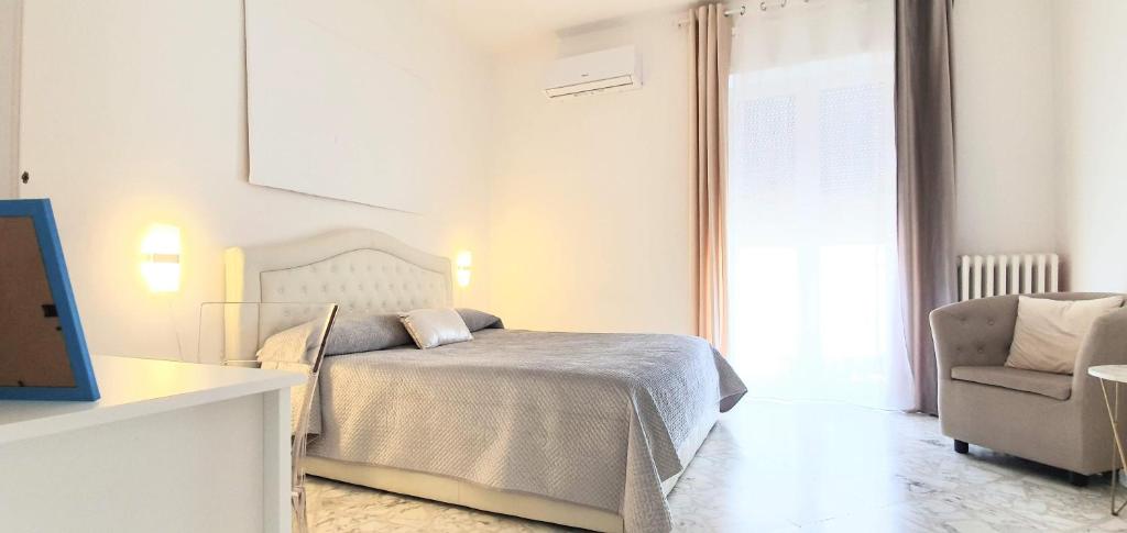 a white bedroom with a bed and a chair at Angela's Apartment. Elegant two bedroom house in Irsina in Irsina