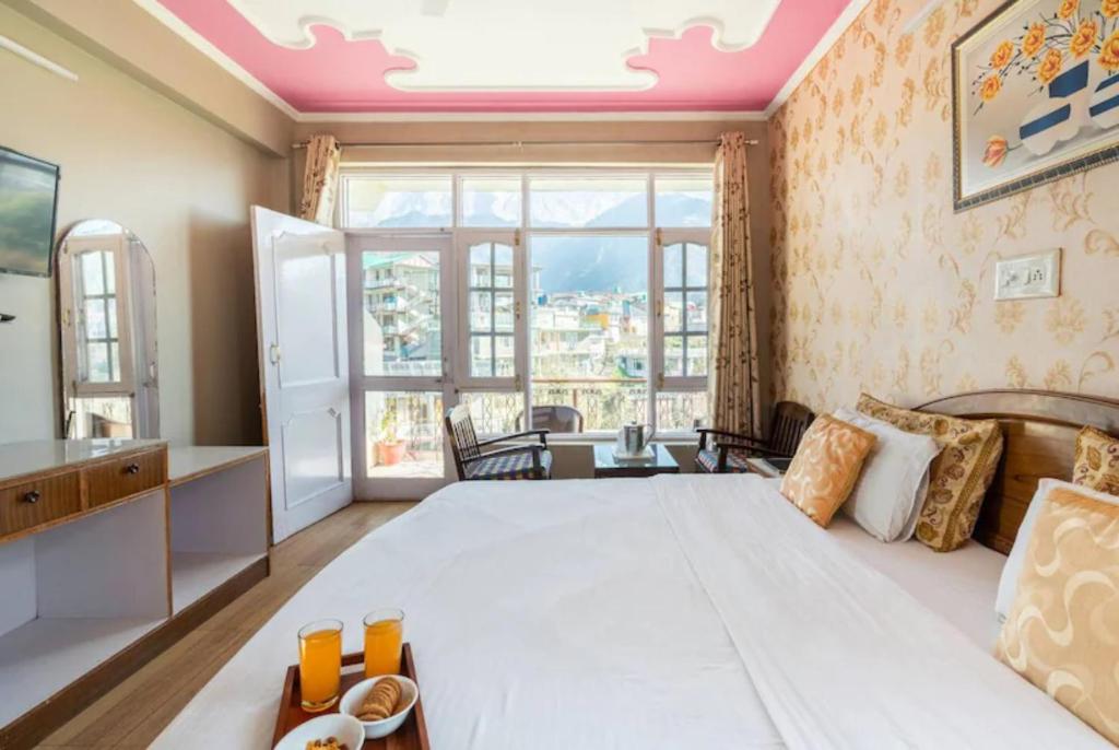 a bedroom with a large bed and a large window at Hotel Snow Crest Inn - Natural landscape Mountain View in Dharamshala