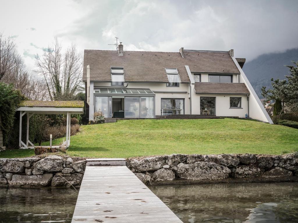 une maison sur une colline avec un pont sur un plan d'eau dans l'établissement Venez Chez Vous Les Pieds dans l'Eau, à Sévrier