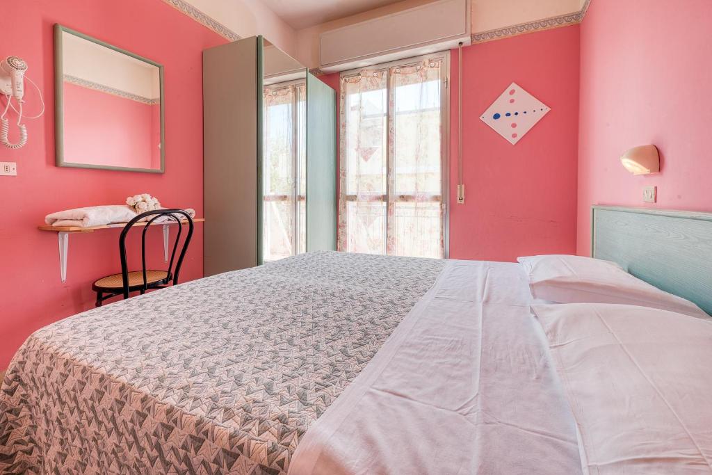 um quarto com uma cama grande e paredes cor-de-rosa em Hotel Sabbia d'Oro em Rimini