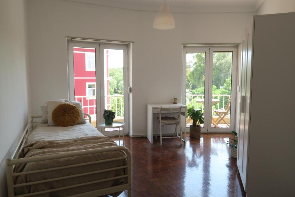 sypialnia z łóżkiem, biurkiem i oknami w obiekcie Lisbon Key Hub - Rooms 6-10 w Lizbonie