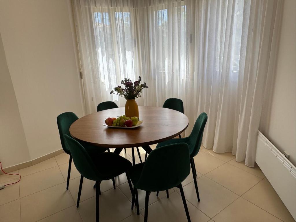 a dining room table with green chairs and a vase of flowers at Paez Villa in Protaras
