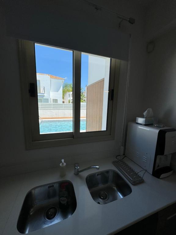 a kitchen counter with two sinks and a window at Paez Villa in Protaras