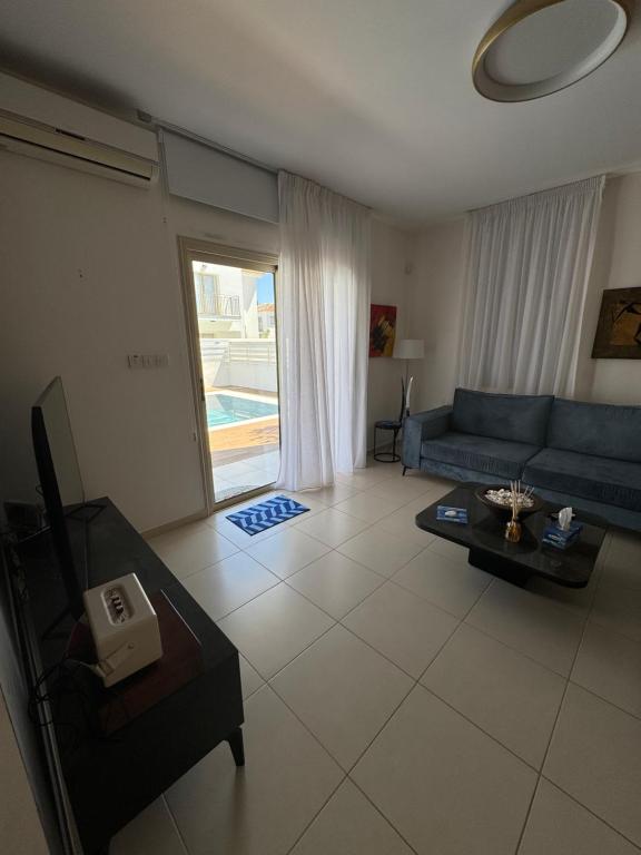 a living room with a blue couch and a table at Paez Villa in Protaras