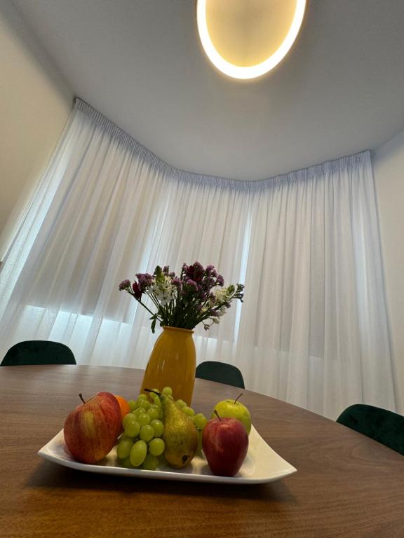 a plate of fruit on a table with a vase of flowers at Paez Villa in Protaras