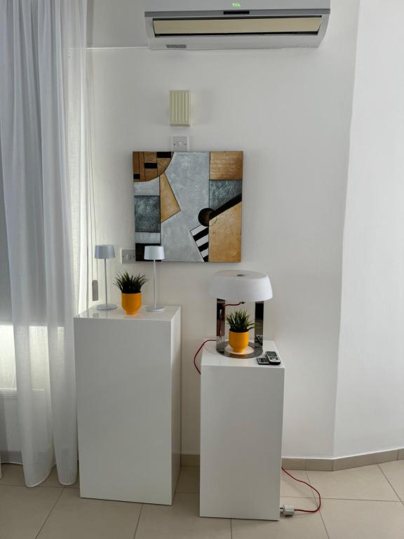two white tables in a room with a painting at Paez Villa in Protaras