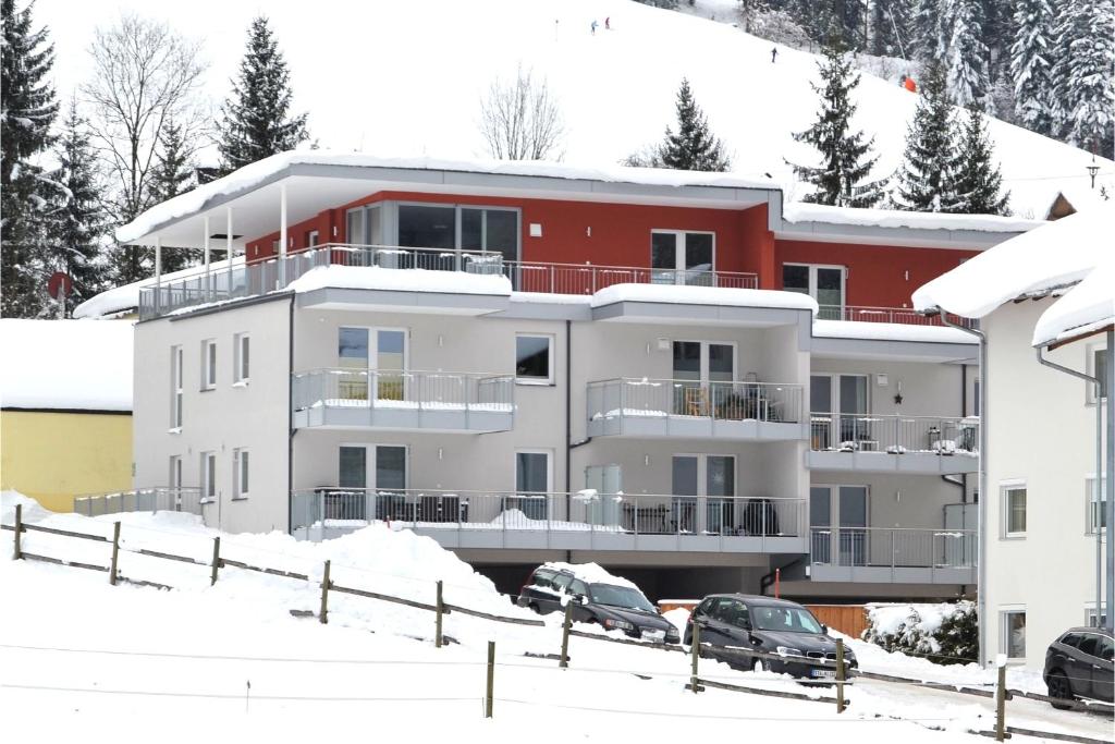a building in the snow with cars parked in front at Panoramaresidenz Scheffau am Wilden Kaiser in Scheffau am Wilden Kaiser