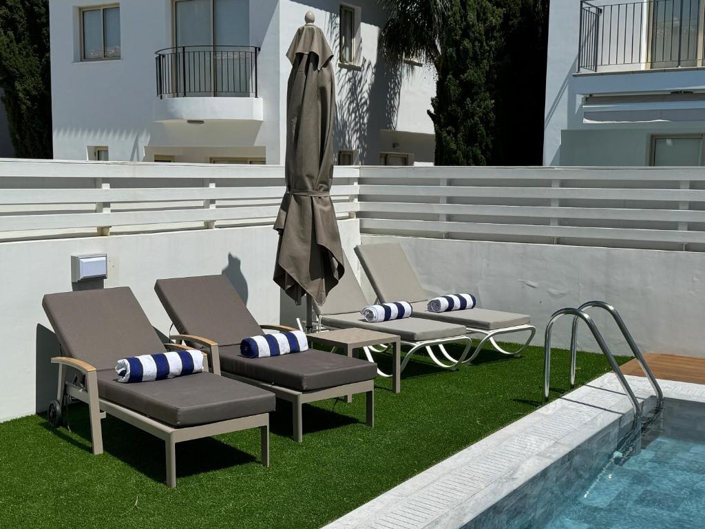 two chairs and an umbrella next to a pool at Paez Villa in Protaras