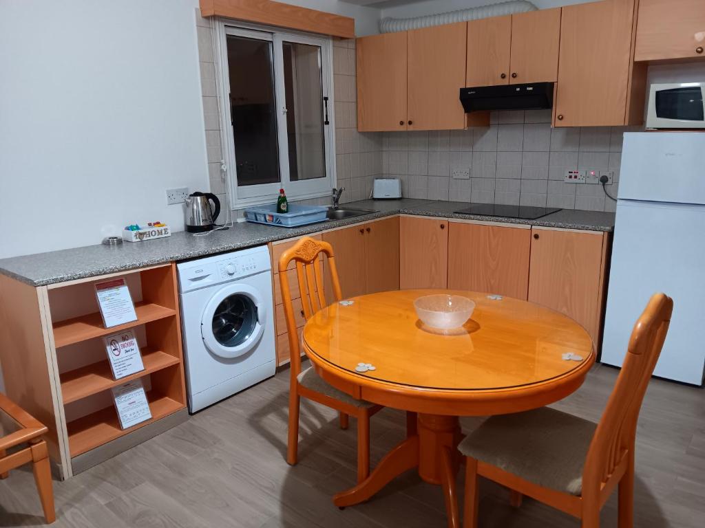 a kitchen with a wooden table and a washing machine at Pari Holiday apartments in Paphos