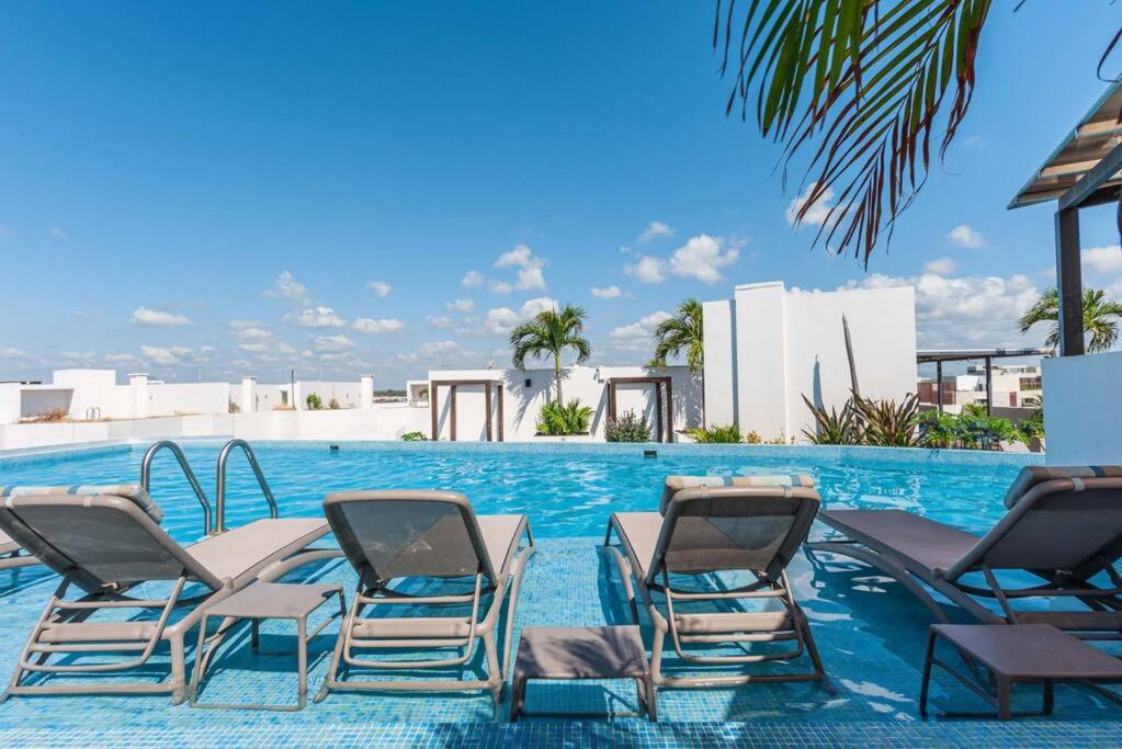 un grupo de sillas de jardín en una piscina en Luxury 2-bed Apartment 200MB Wifi Sauna AC Gym en Playa del Carmen