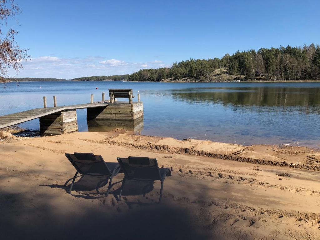 two chairs sitting on a beach next to a dock at Stuga Pörsvik in Nauvo