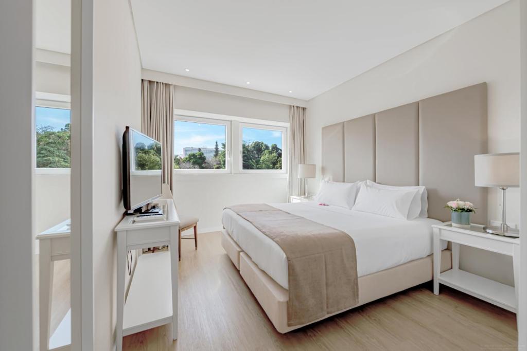 a white bedroom with a bed and a television at Lisboa Central Park Hotel Suites & Studios in Lisbon