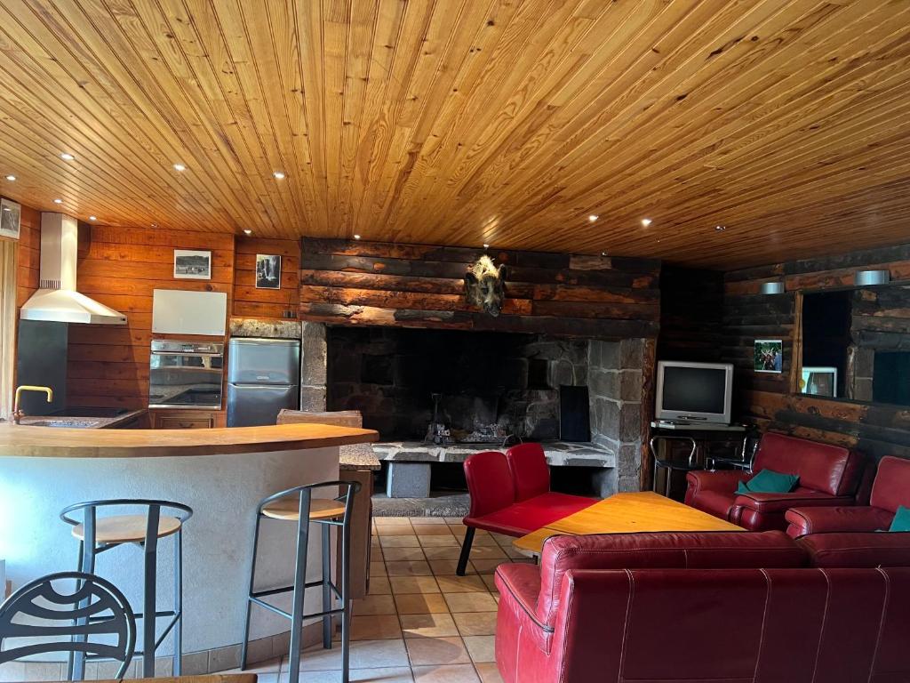 een keuken en een woonkamer met rode stoelen en een bar bij Maison au Giraldès Le Claux Puy Mary Volcan chalet in Le Claux