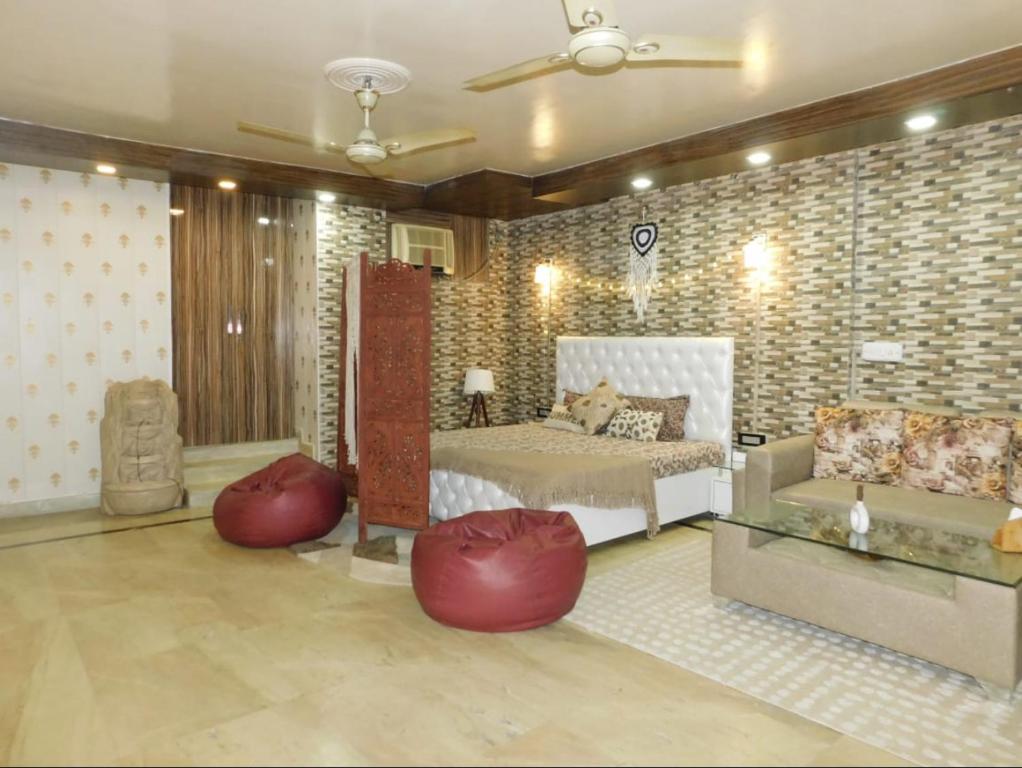 a bedroom with a bed and two red ottomans at Cozy Bohemian Studio Apartment - GK2 South Delhi, near M Block Market in New Delhi