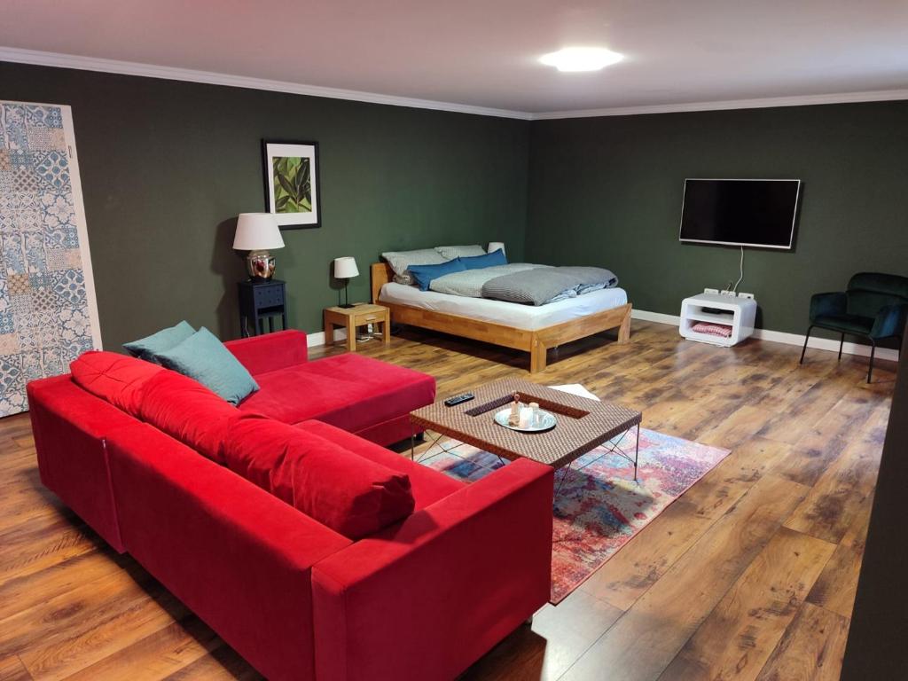 sala de estar con sofá rojo y cama en Suite Vorderrhön Anní, en Unsleben