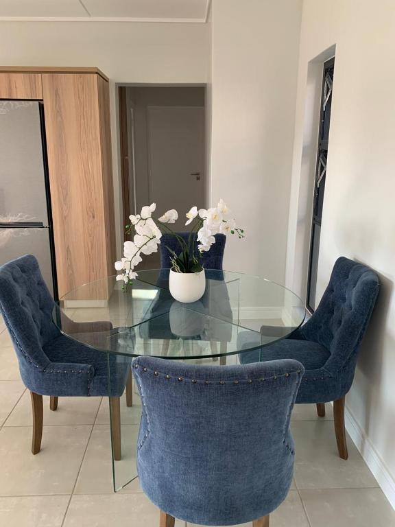 a glass table with blue chairs and a vase of flowers at Guthulele Living in Ballito
