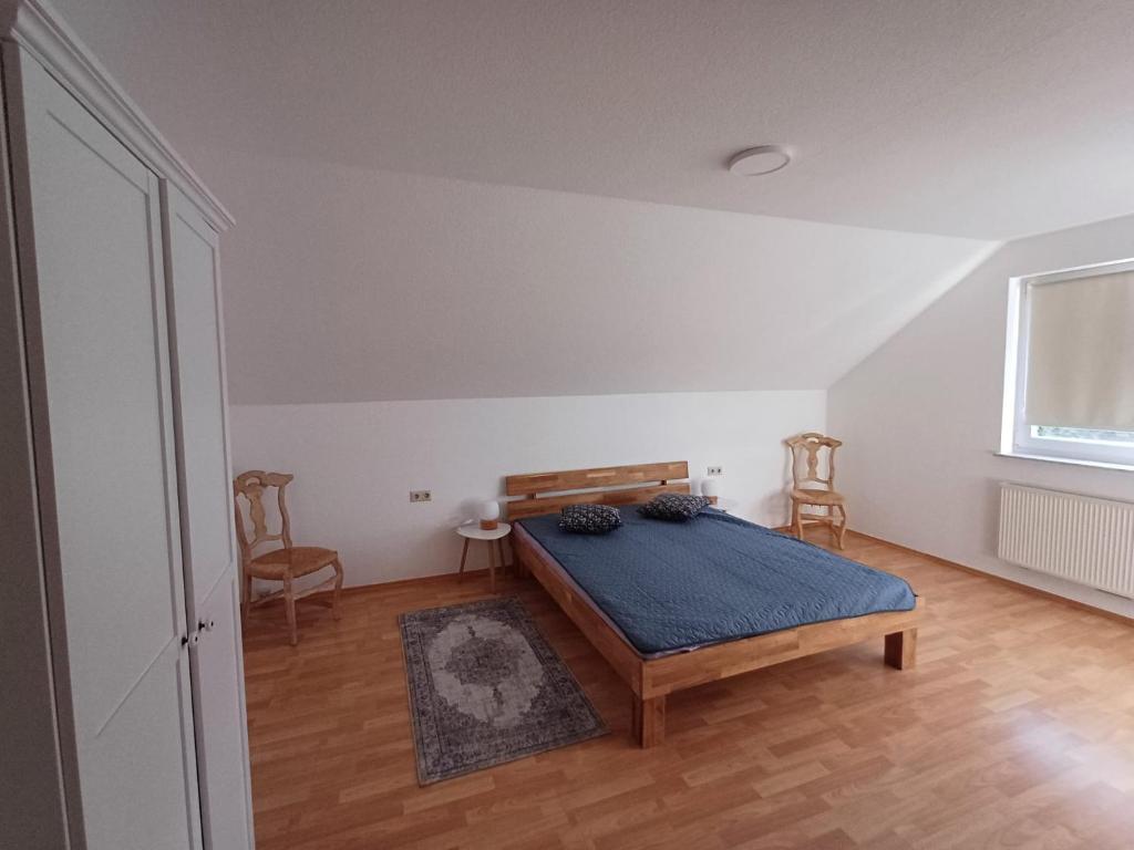 1 dormitorio con 1 cama, 2 sillas y ventana en Naturerlebnis Ferienhaus, en Neunkirchen