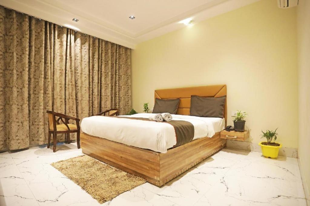 een slaapkamer met een groot bed met een houten hoofdeinde bij Hotel Royal Paradise - Mahipalpur Delhi Airport in New Delhi