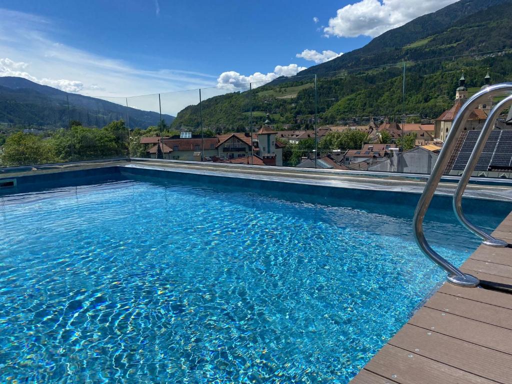 a large swimming pool with mountains in the background at Dominik Alpine City Wellness Hotel - Adults only in Bressanone