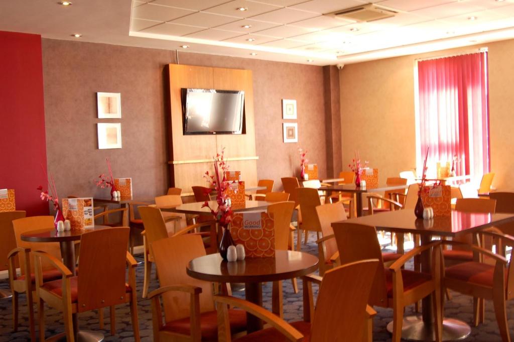 comedor con mesas y sillas y TV en Holiday Inn Express Swindon City Centre, an IHG Hotel, en Swindon
