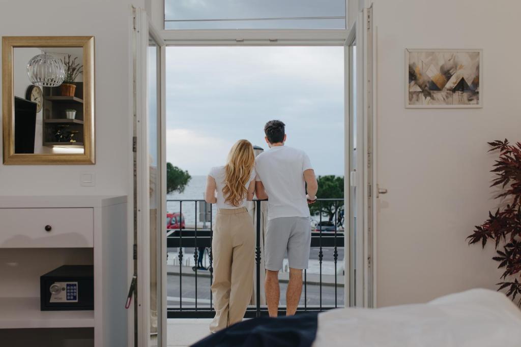 un homme et une femme debout sur un balcon donnant sur la porte dans l'établissement Blue Pearl Elite Apartments, à Piran