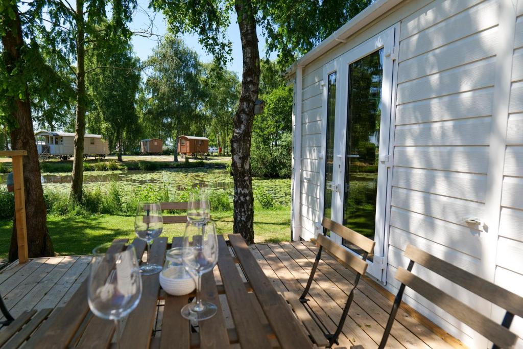 una mesa con copas de vino en una terraza de madera en Vakantiehuis Hoge Kempen - 25 minuten Roermond, Maasmechelen & Maastricht, en Kinrooi