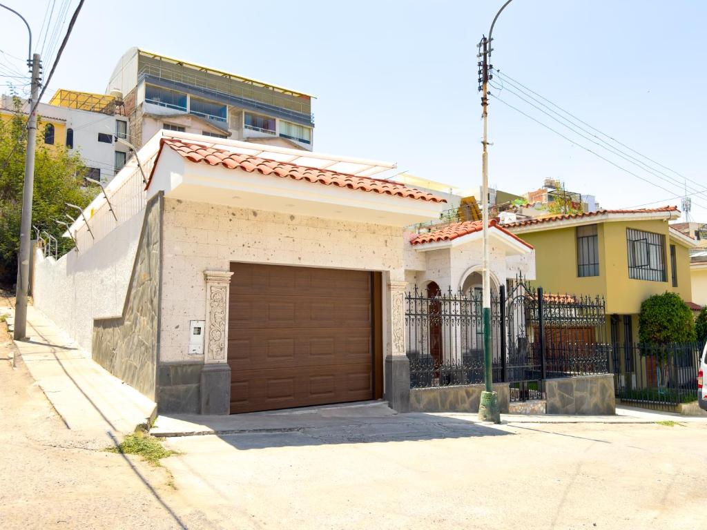 une maison blanche avec un garage marron dans l'établissement Casa Vallecito, à Arequipa