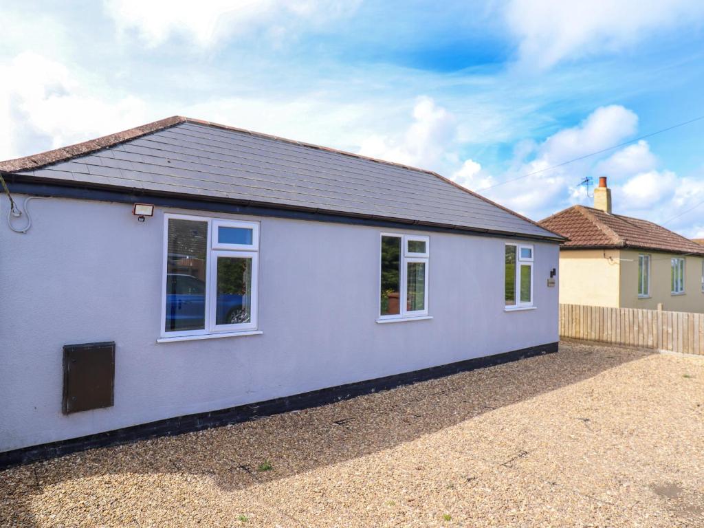 a white house with white windows on a gravel driveway at Gordona in Mablethorpe