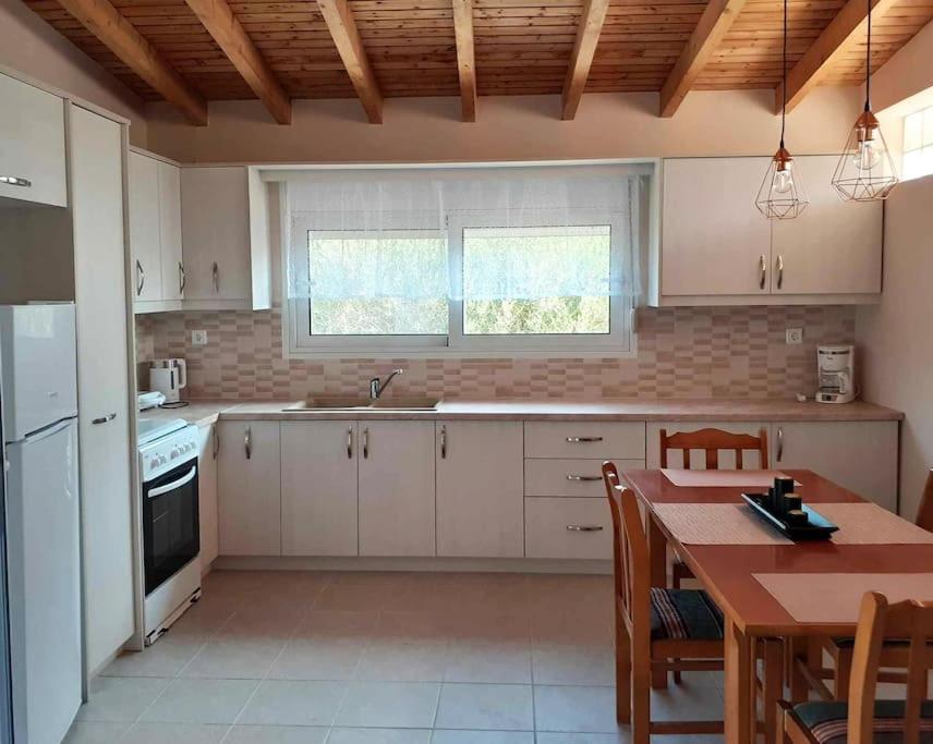 a kitchen with white cabinets and a wooden ceiling at House Eleni in Kranidi