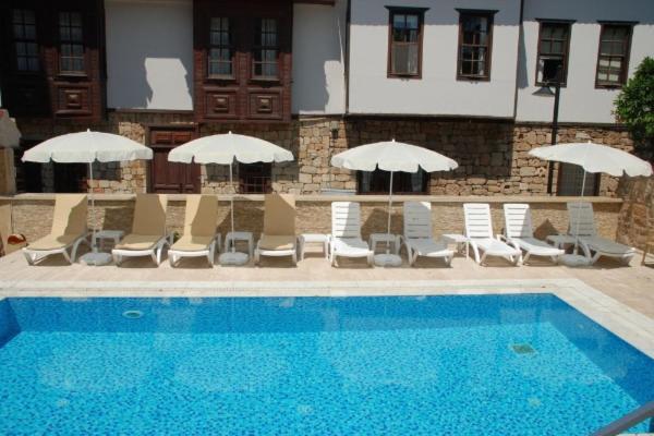 Alanya Comfort - 4 Star Beautiful Apartments between Cleopatra Beach 1 and Harbor في ألانيا: مسبح وكراسي ومظلات بجانب مبنى