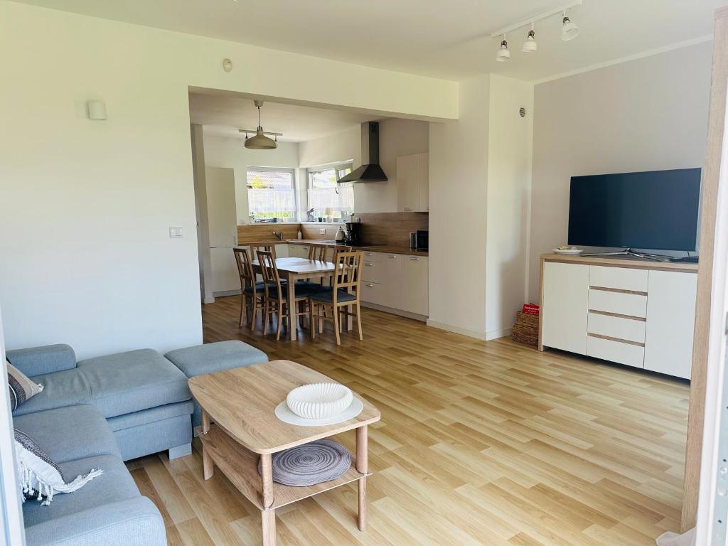 uma sala de estar com um sofá azul e uma mesa em Porto 13 - TRZĘSACZ SUNNY SIDE BALTIC em Trzęsacz