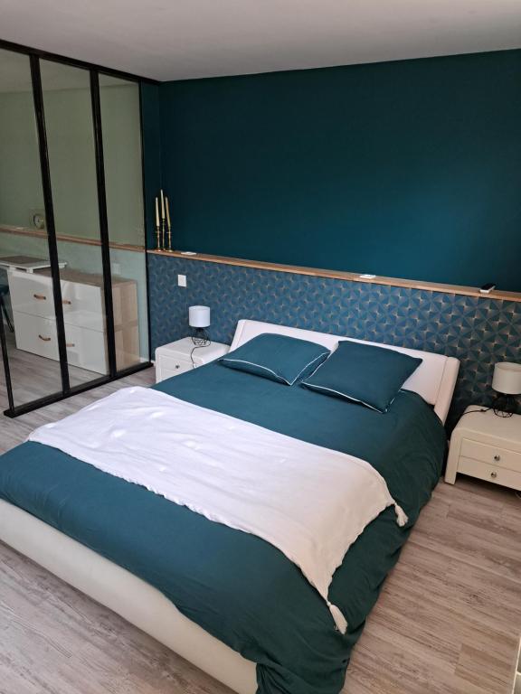 sypialnia z dużym łóżkiem i niebieską ścianą w obiekcie Chambre proche circuit 24h w mieście Le Mans