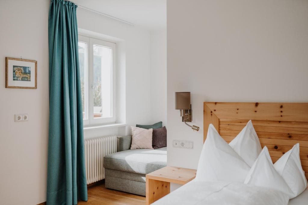 um quarto com uma cama, um sofá e uma janela em Hotel Berghaus Rosengarten em Nova Levante