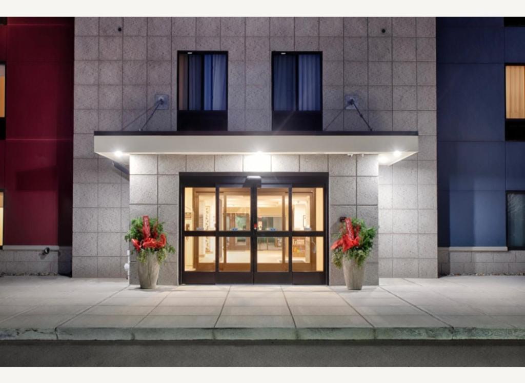 un bâtiment avec deux plantes en pot devant une porte dans l'établissement Candlewood Suites Detroit Sterling Heights, an IHG Hotel, à Waldenburg