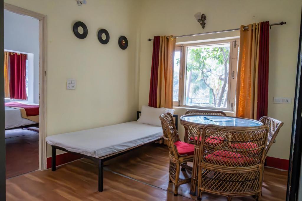 um quarto com uma mesa e cadeiras e uma janela em Dew Drops Homestay em Nainital