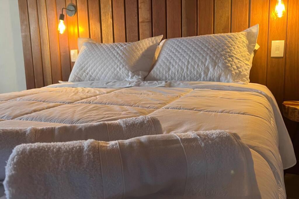 ein großes Bett mit weißer Bettwäsche und Kissen in der Unterkunft Chalé Causo Bão in Costas