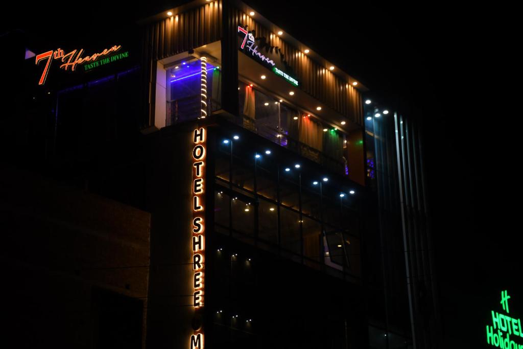 una señal de neón en el lateral de un edificio por la noche en Hotel Shree Om en Jumri TilaiyÄ
