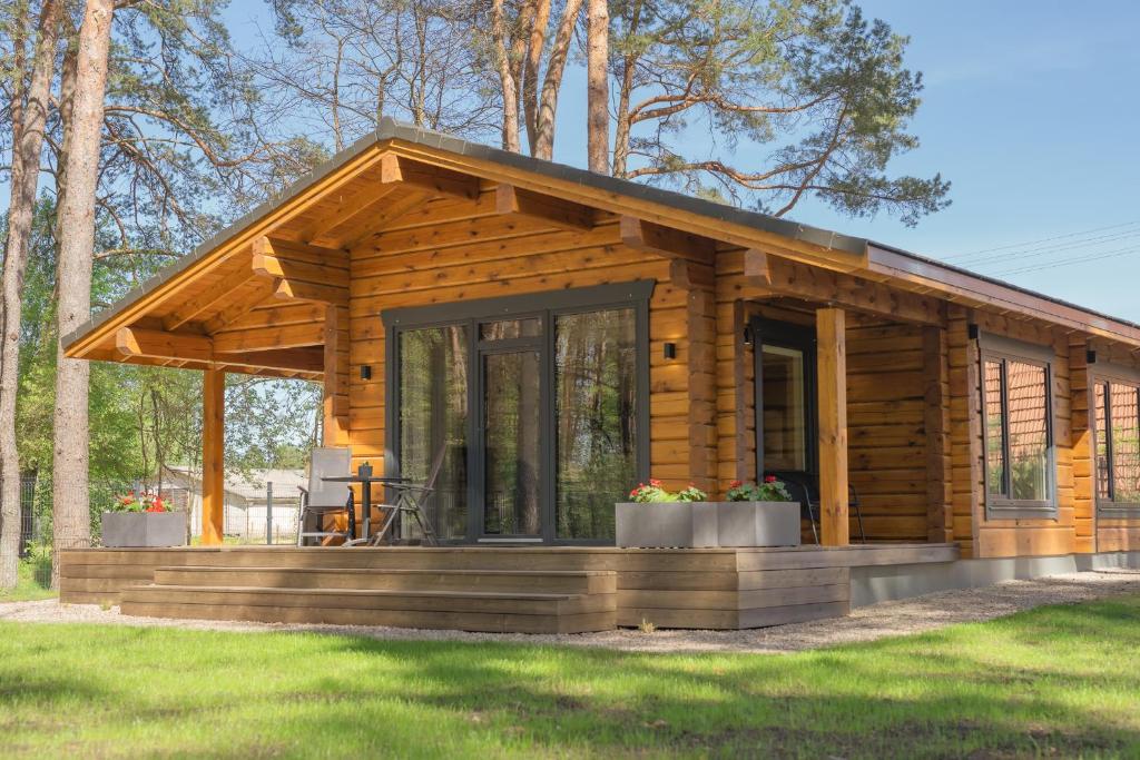 a log cabin with a porch in the grass at Hipo House in Utena