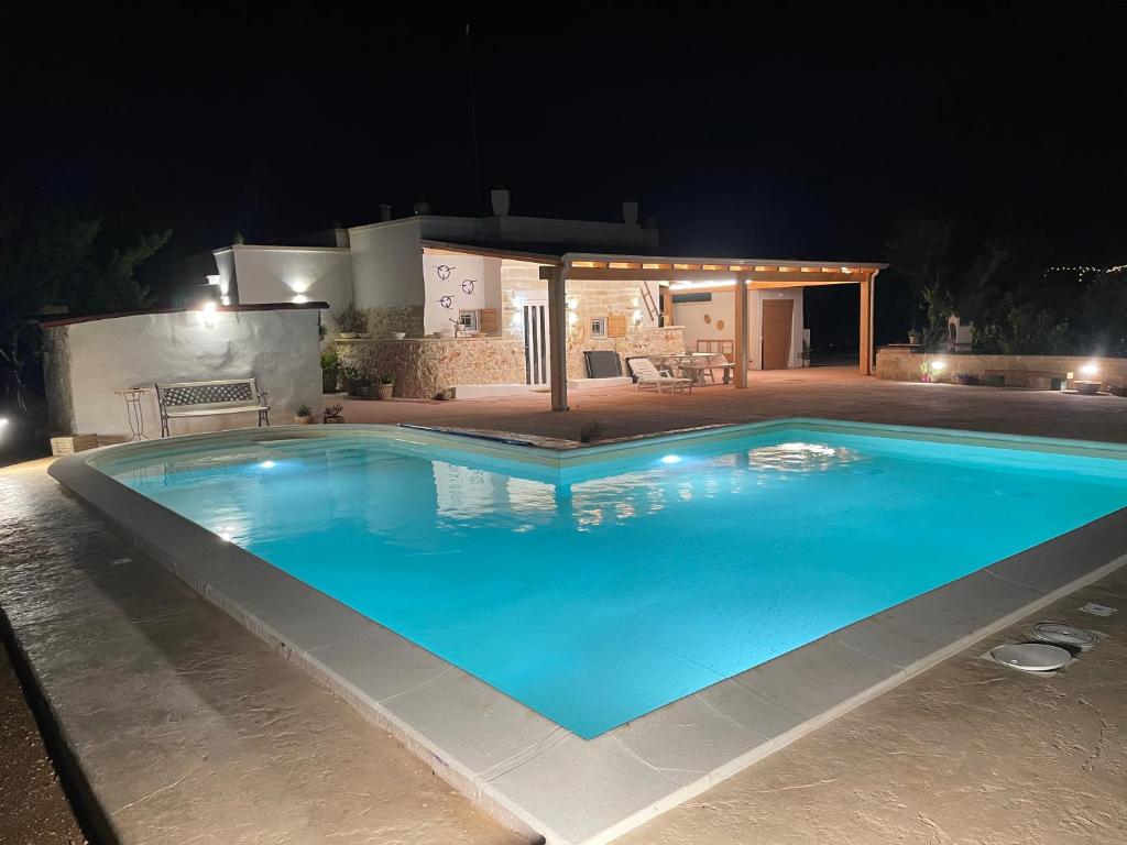 ein großer blauer Pool in der Nacht in der Unterkunft Trullo Del Salento in San Vito dei Normanni
