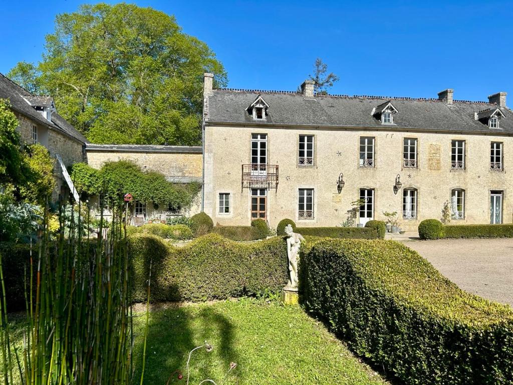 una casa grande con un seto delante de ella en Chambres d'Hôtes Manoir Du Chêne en Nonant