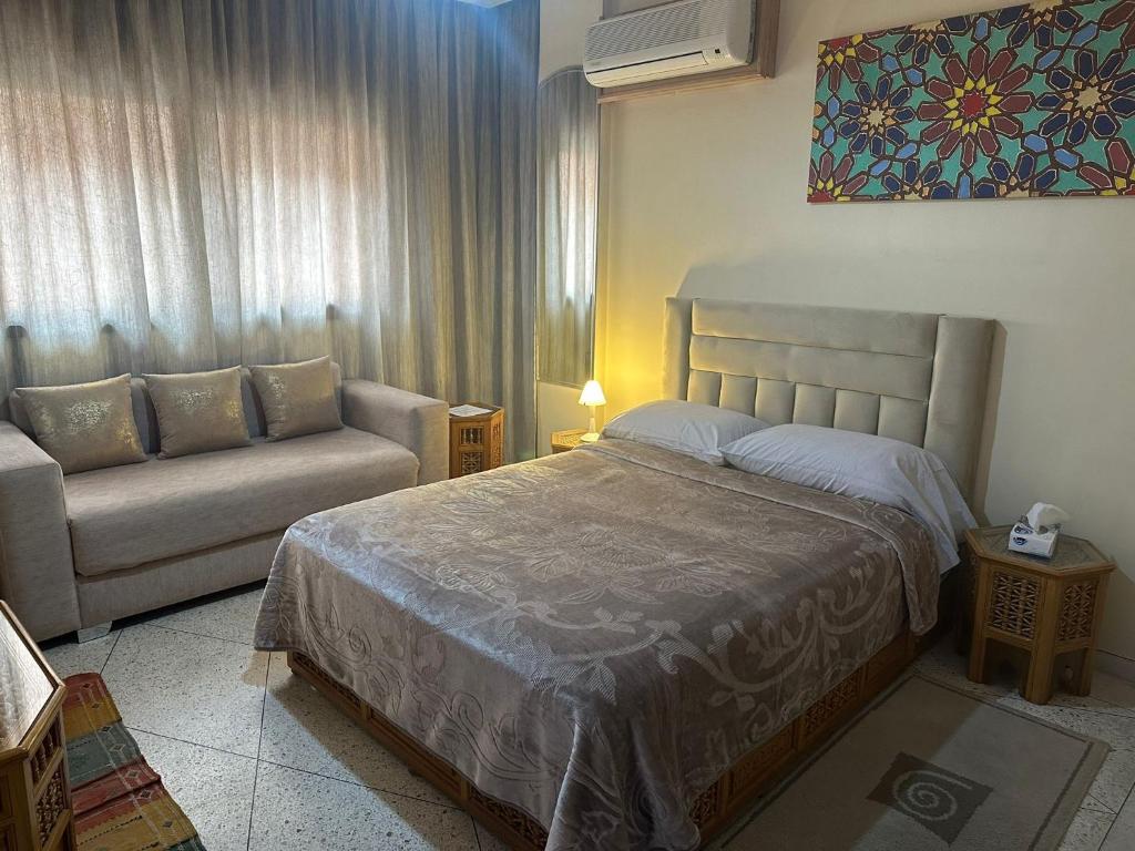 Appartement Wassim - Gueliz في مراكش: غرفة نوم بسرير واريكة