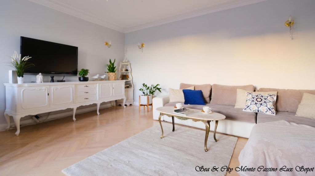 a living room with a couch and a tv at Sea & City 50 m Monte Casinno 100 m Beach Apartments Lux Sopot in Sopot