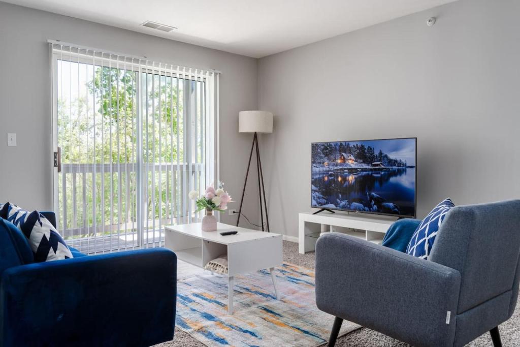 a living room with two blue chairs and a tv at Corporate Housing by MGM in Gurnee
