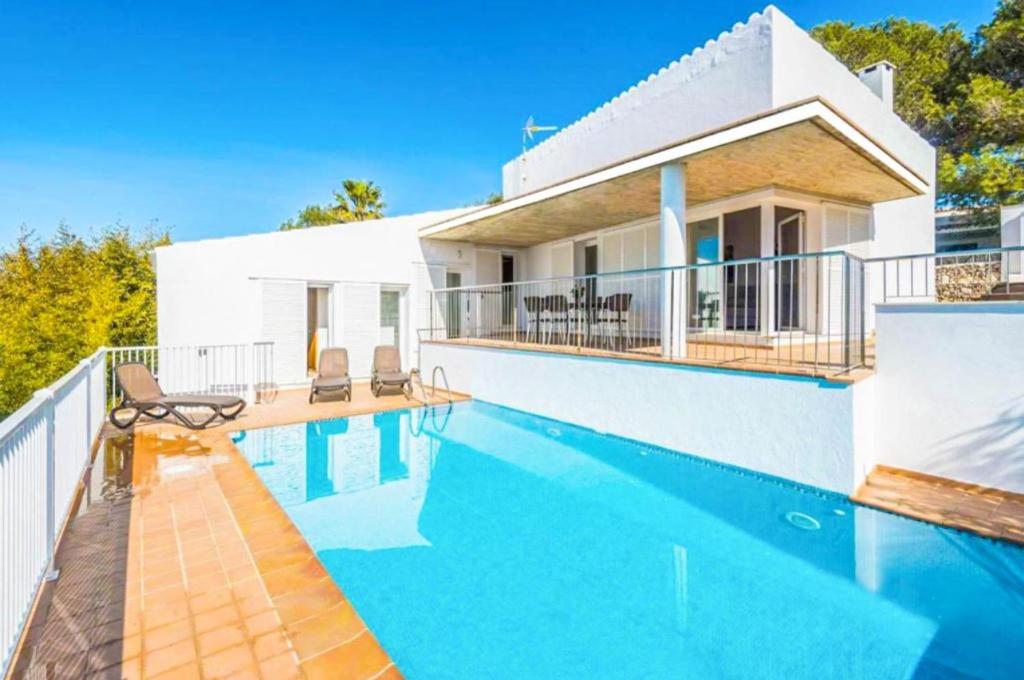 a villa with a swimming pool in front of a house at Villa Casa Xaloc in Binibeca