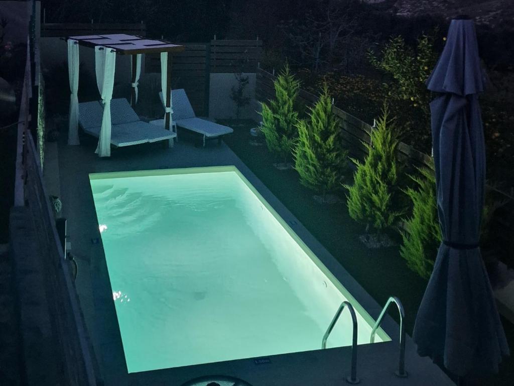 einen Pool in der Nacht mit einem Tisch und Sonnenschirmen in der Unterkunft Elia Paradise Villa with Pool in Iraklio